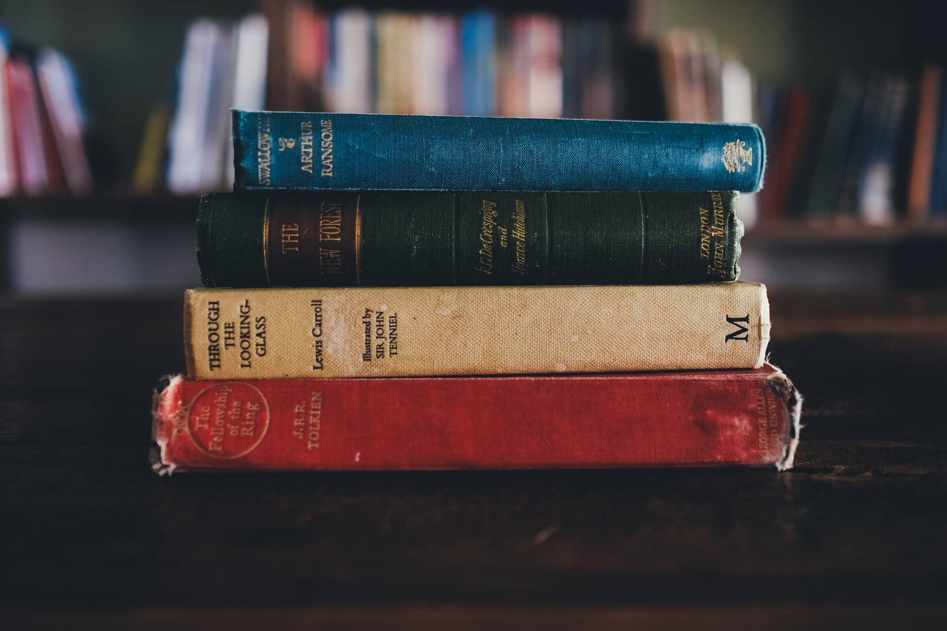 lord of the rings, through the looking glass and some other fantasy books stacked in a pile